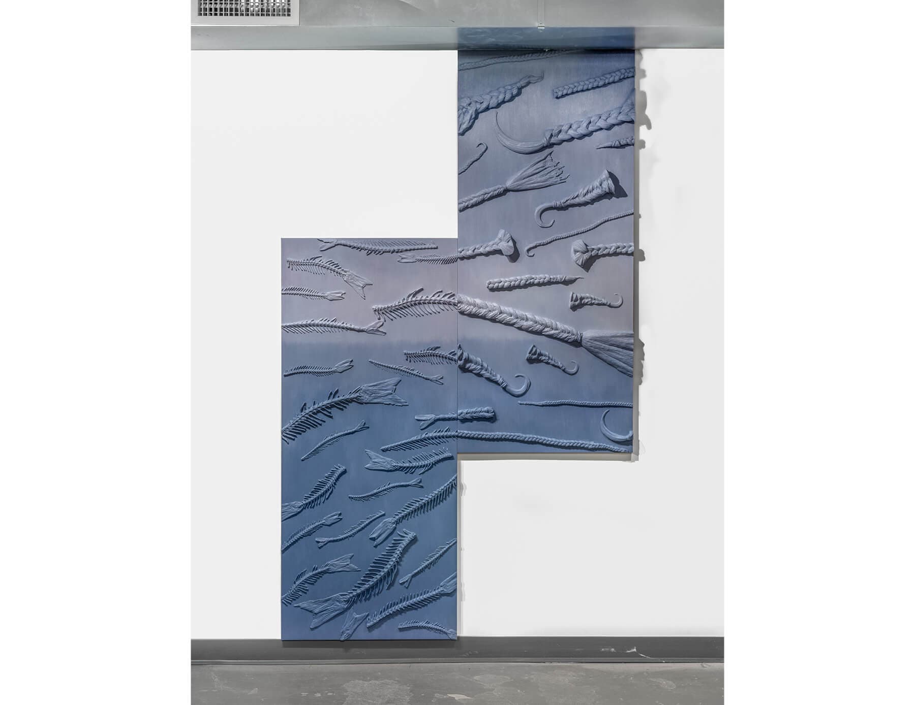 Lucy Kim's design of fish bones and braids, rendered in blue, is displayed against a white wall.