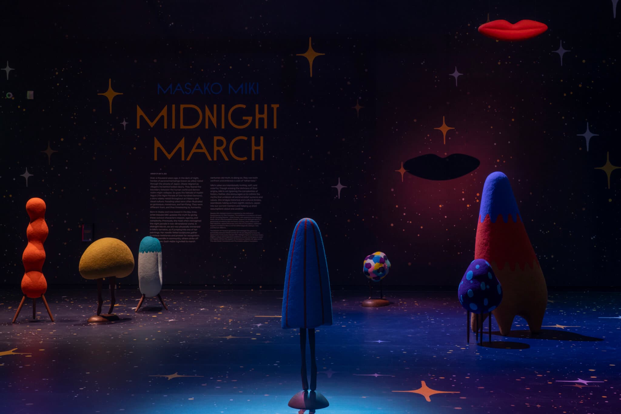 Felted wool sculptures positioned in a dimly lit room.